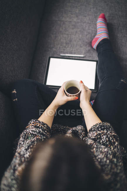 Top view of woman sitting on the couch with tablet and cup of coffee — Stock Photo