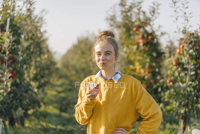 Giovane donna che mangia mela nel frutteto di mele — Foto stock