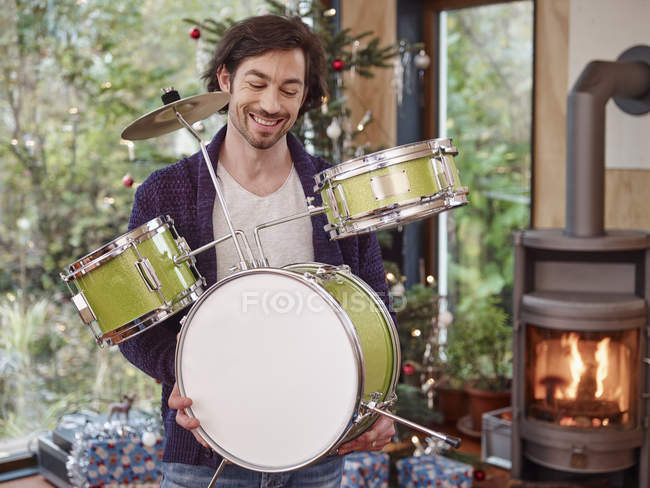 Man with toy drums by the Christmas tree — Stock Photo