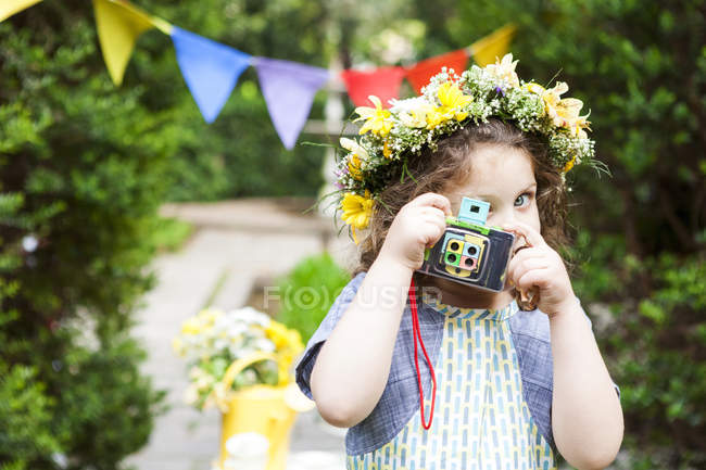 Menina vestindo flores tirando uma foto com câmera vintage — Fotografia de Stock