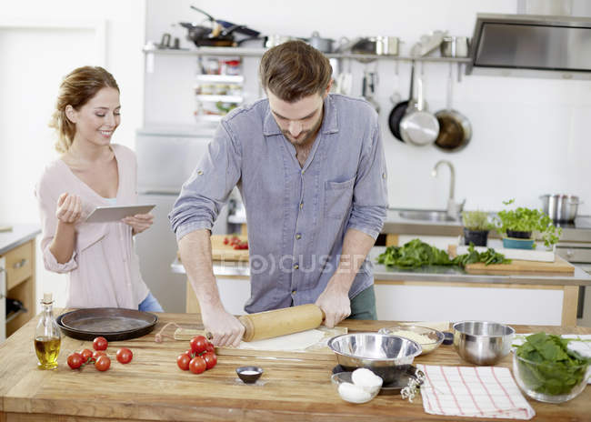 Couple preparing pizza dough in kitchen — Stock Photo