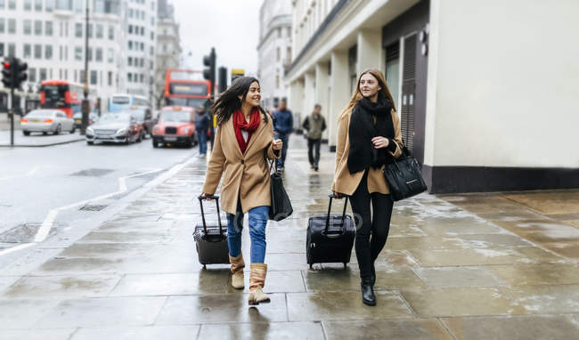 Due amici alla scoperta della città, in arrivo con trolley bags, Londra, Regno Unito — Foto stock