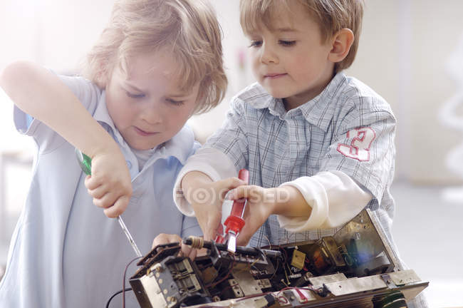 Two little boys disassembling an old radio — Stock Photo