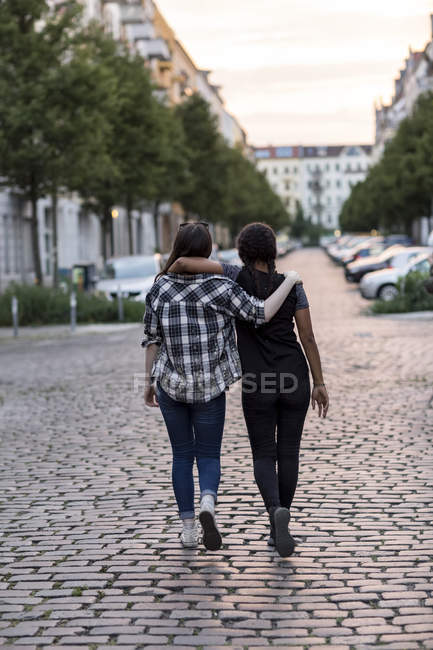 Two teenage girls walking on hugging — Stock Photo