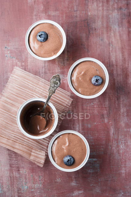 Sobremesa de creme de chocolate com mirtilos em xícaras na superfície marrom gasto — Fotografia de Stock