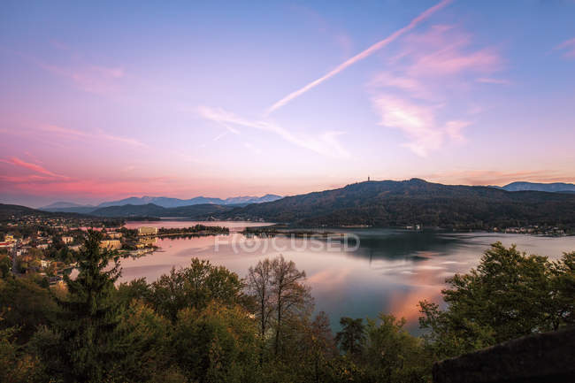 Österreich, Kärnten, Pörtschach, See und Bäume am Ufer bei Sonnenuntergang — Stockfoto