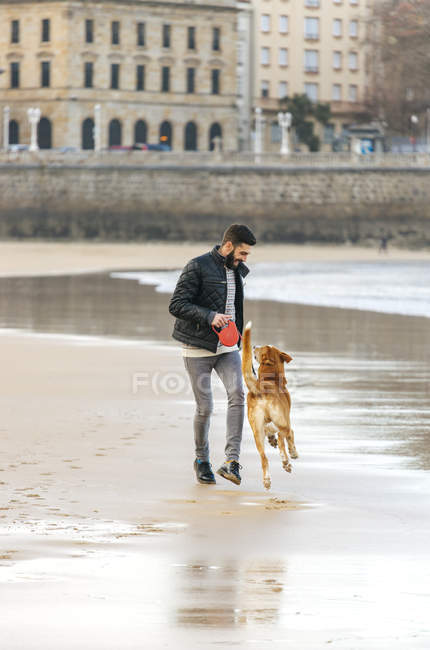 Spanien, gijon, mann spielt am strand mit seinem hund — Stockfoto