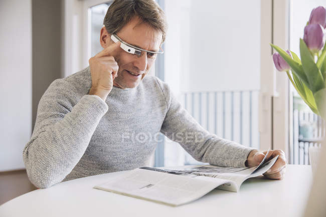 Uomo con display ottico montato sulla testa che legge una rivista — Foto stock