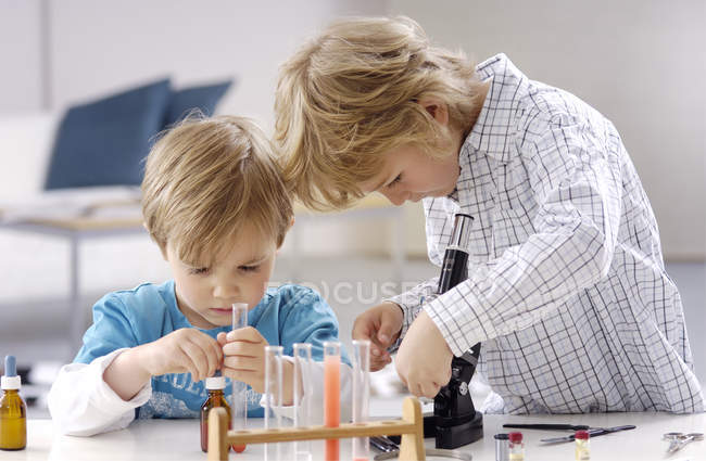 Dos niños jugando con utensilios de laboratorio químico - foto de stock