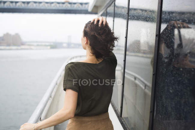 Estados Unidos, Nueva York, joven mujer de pie en un barco de excursión en un día ventoso - foto de stock