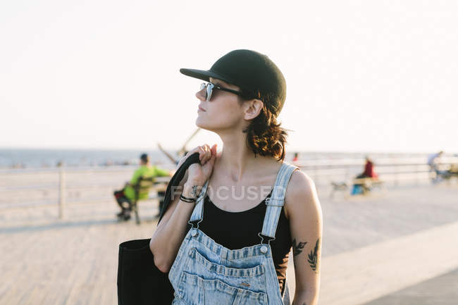 Jovem mulher no calçadão da praia ao pôr do sol — Fotografia de Stock