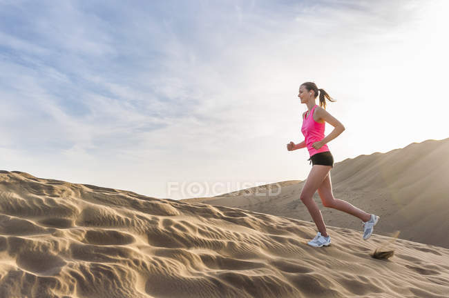 Giovane donna che corre sulla spiaggia — Foto stock