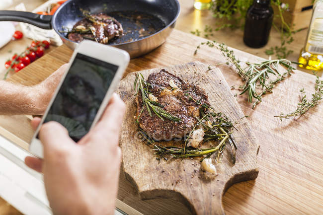 Homem tirando foto celular de bifes preparados — Fotografia de Stock