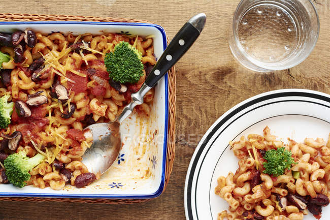 Macaroni, broccoli, kidney beans, tomato sauce, onions and garlic in baking dish — Stock Photo