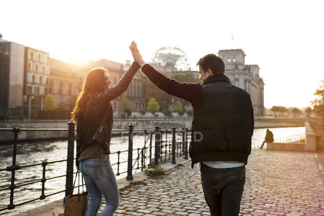 Germany, Berlin, young walking along River Spree high fiving — Stock Photo
