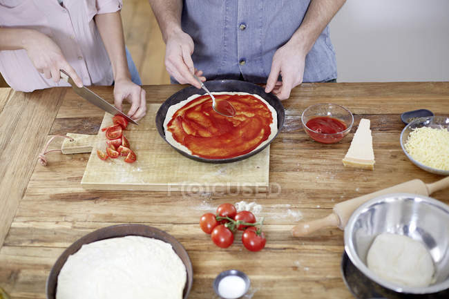Couple preparing pizza in kitchen — Stock Photo