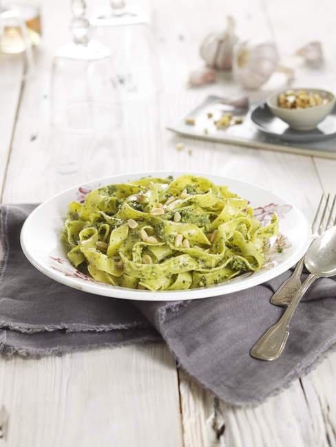 Pasta with green pesto serving on white wooden table — Stock Photo