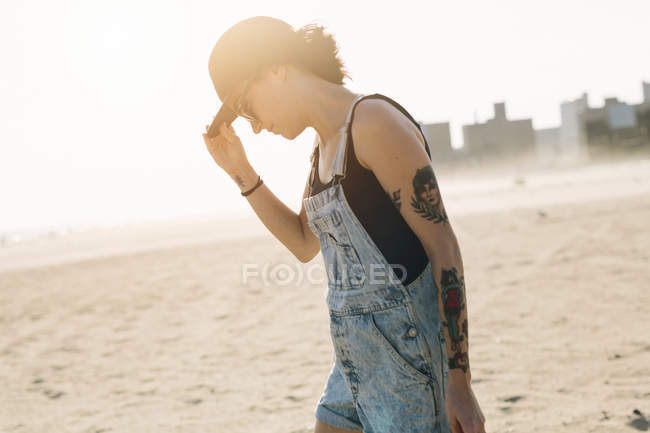 Jovem mulher de pé na praia ao pôr do sol — Fotografia de Stock