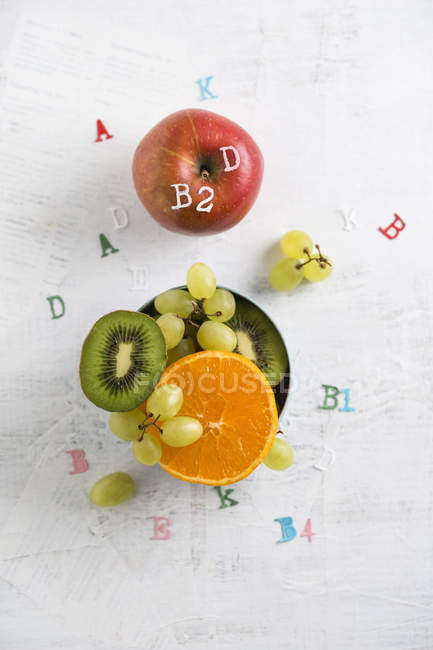 Banane, apple, orange, kiwi and green grapes, different vitamins — Stock Photo