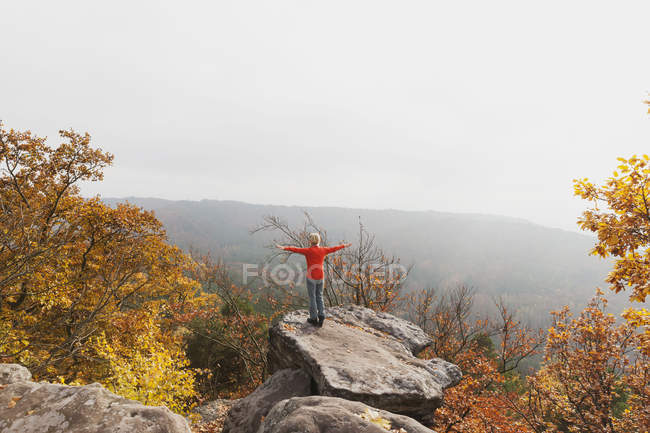 Alemania, Renania Palatinado, Bosque Palatinado, mujer practicando yoga en Drachenfels en otoño - foto de stock