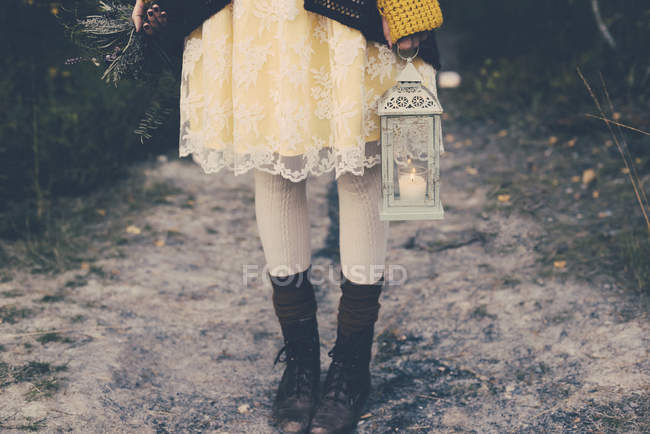Старомодний стиль Жінка тримає пучок квітів і буря лампа, частковим видом — стокове фото