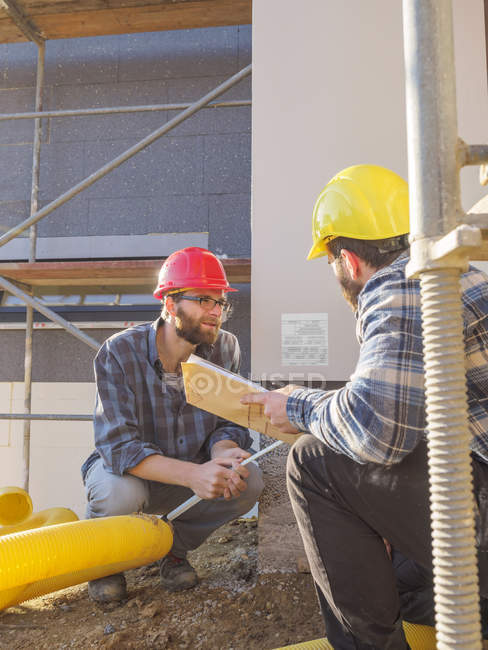 Artisans discutant sur le chantier de construction — Photo de stock