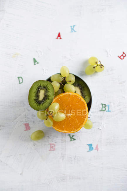 Banane, apple, orange, kiwi and green grapes, different vitamins — Stock Photo