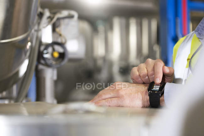 Close-up of male hands using smartwatch in industrial plant — Stock Photo