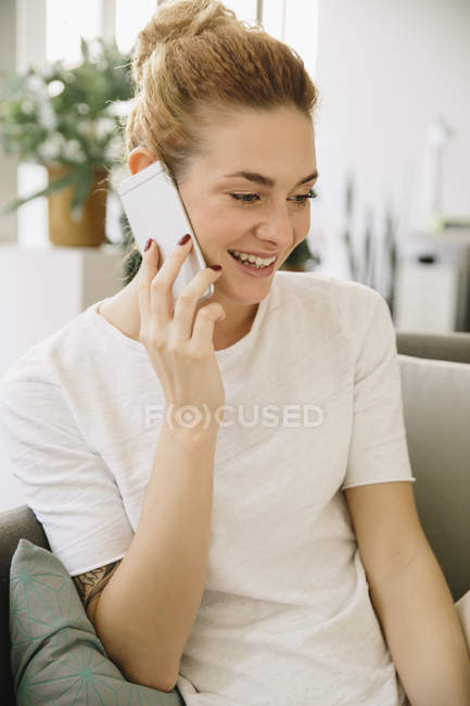 Jeune femme à la maison parlant sur son téléphone portable — Photo de stock
