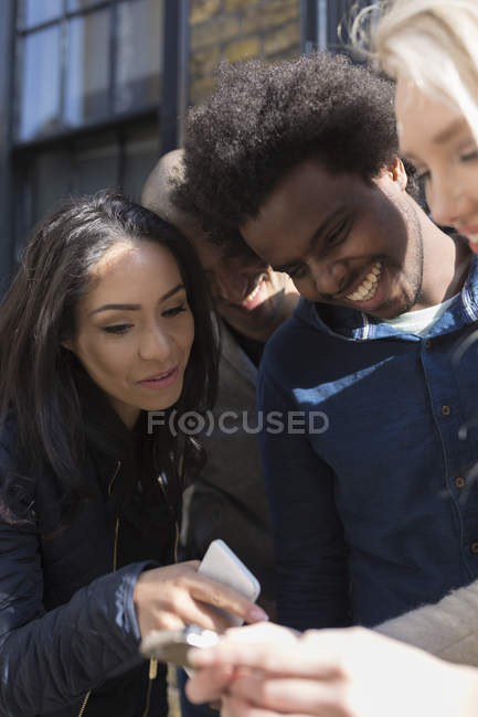 Amici felici che condividono il cellulare sulla strada — Foto stock