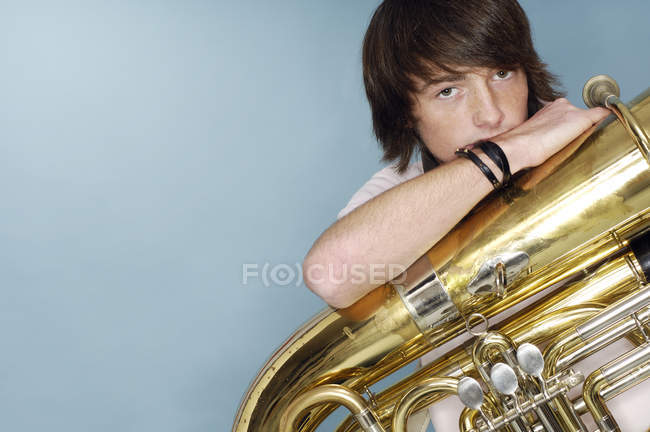Portrait de garçon adolescent avec tuba devant fond bleu — Photo de stock