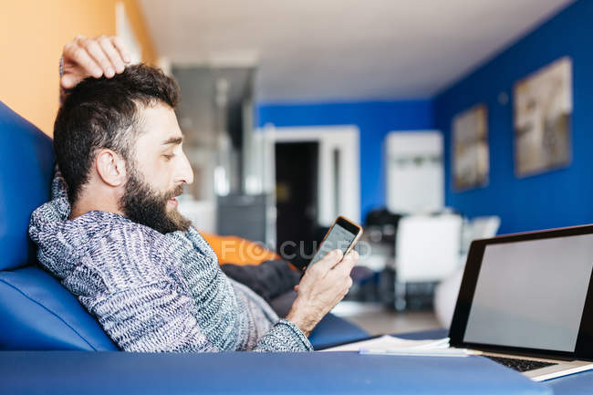 Hombre usando el ordenador portátil y el teléfono móvil - foto de stock
