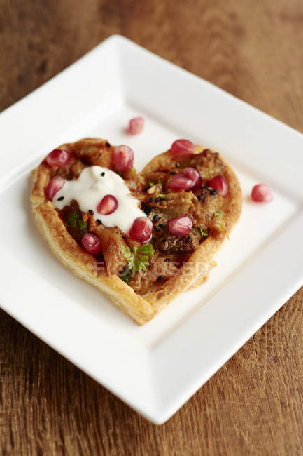 Heart shaped puff pastry tarts with eggplant and pomegranate arils — Stock Photo