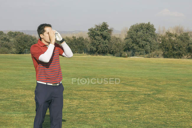 Golfista usando un telémetro láser, campo de golf - foto de stock