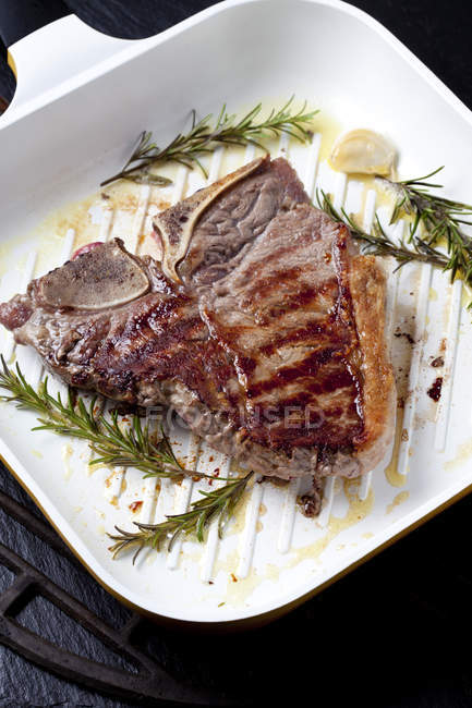 Porterhouse steak avec rosmary et ail dans une poêle à griller — Photo de stock