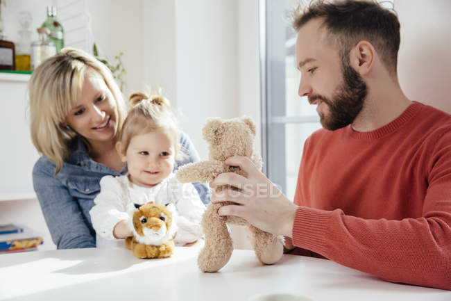 Mother and daughter playing with plush tiger, father with plush bear — Stock Photo
