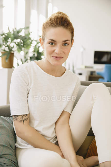 Молодая женщина сидит дома на диване — стоковое фото