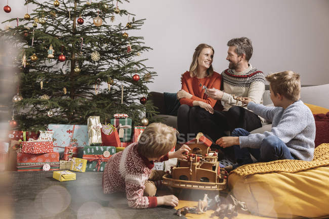 Family unwrapping Christmas gifts and playing with toys — Stock Photo