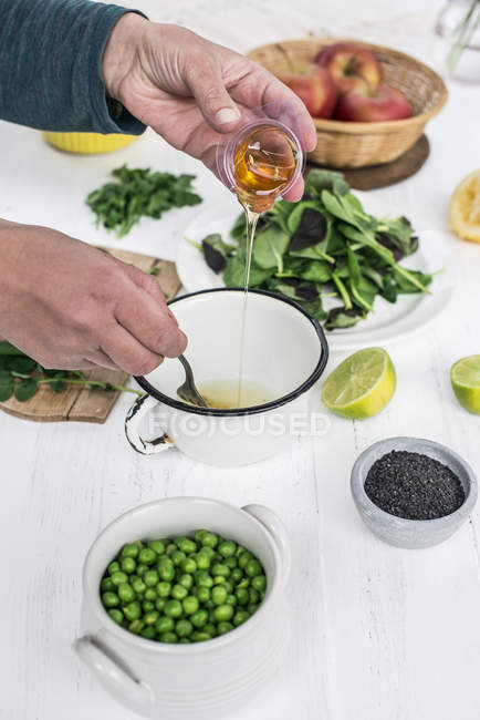 Vue recadrée des mains ajoutant du miel dans la vinaigrette — Photo de stock