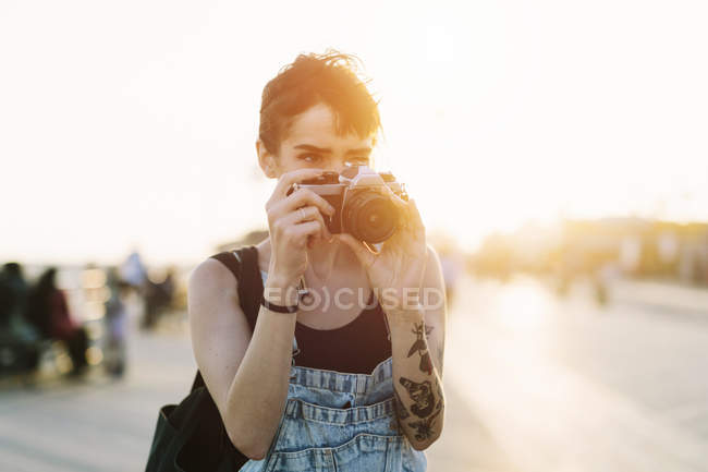 Молодая женщина фотографирует на закате — стоковое фото