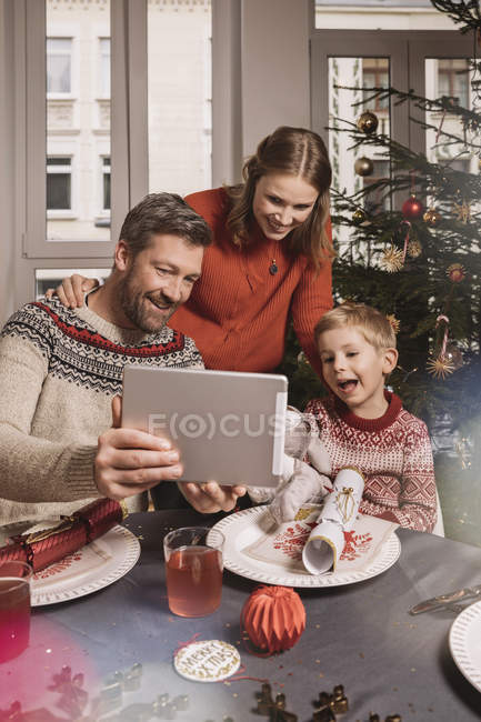 Family using digital tablet at decorated Christmas table — Stock Photo