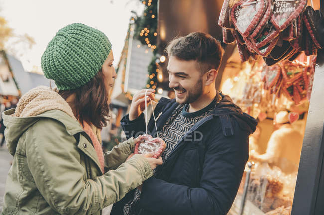Woman receiving a gingerbread heart from her boyfriend on the Christmas Market — Stock Photo