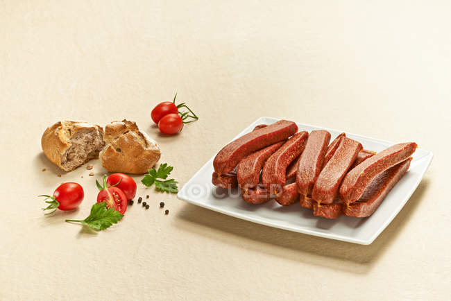Landjaeger, pork sausages on plate over beige background — Stock Photo