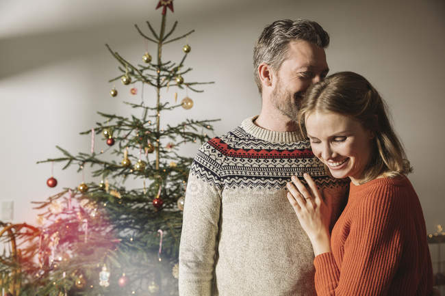 Happy couple hugging in front of Christmas tree — Stock Photo