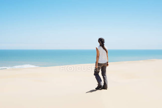 Namibia, Namib deserto, Swakopmund, donna che cammina tra le dune del deserto verso il mare — Foto stock