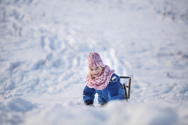 Портрет улыбающейся девушки с санями в снегу — стоковое фото
