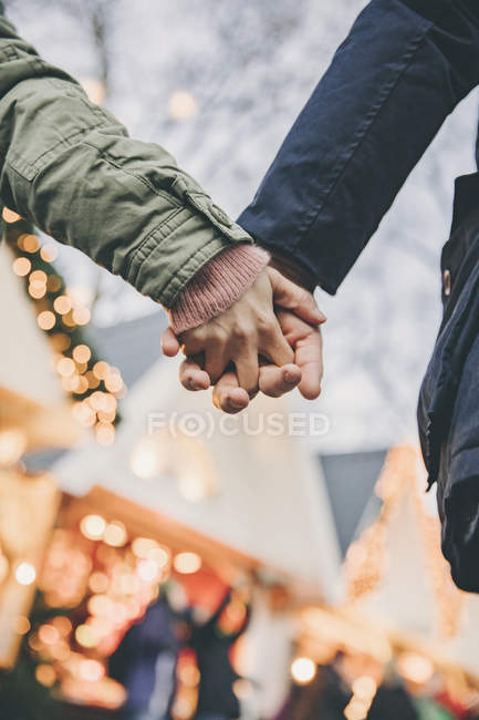 Nahaufnahme eines Paares, das sich auf dem Weihnachtsmarkt an den Händen hält — Stockfoto