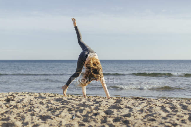 Жінка на пляжі, повертаючи колесо — стокове фото