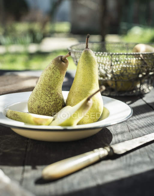 Bowl with whole and sliced pears — Stock Photo
