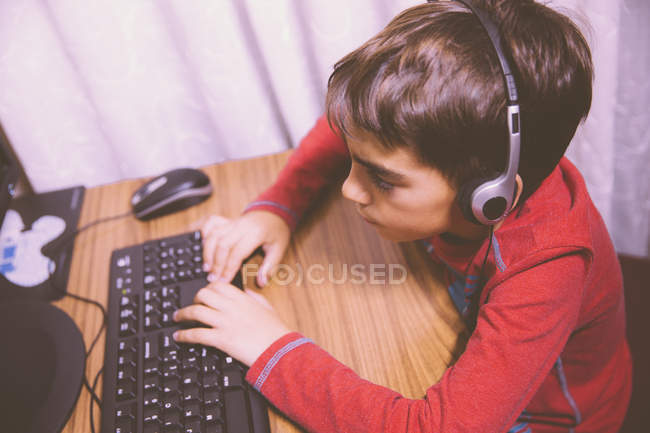 Хлопчик, сидячи за столом і за допомогою комп'ютера — стокове фото